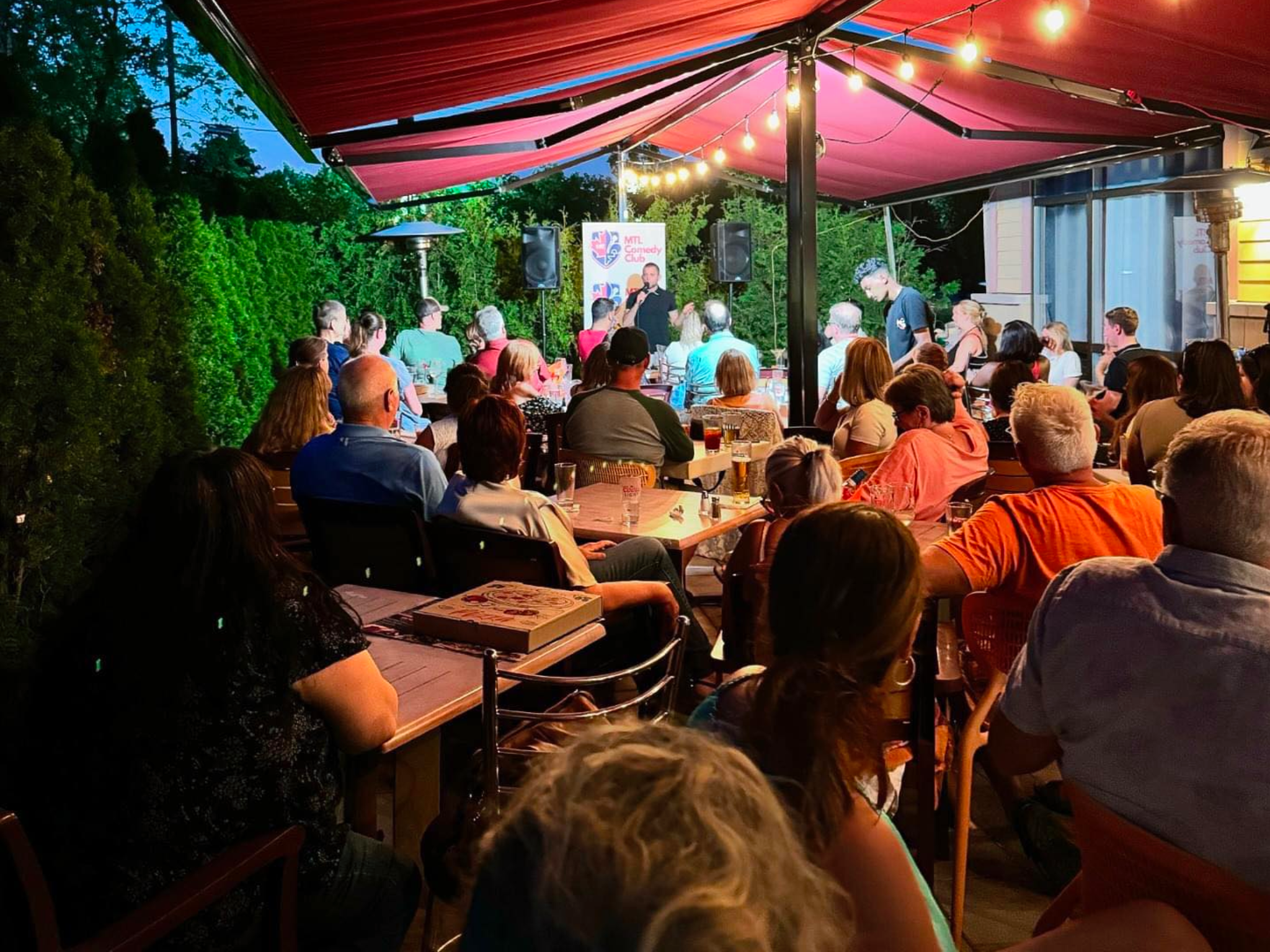 A group of people sitting at tables under an umbrella.